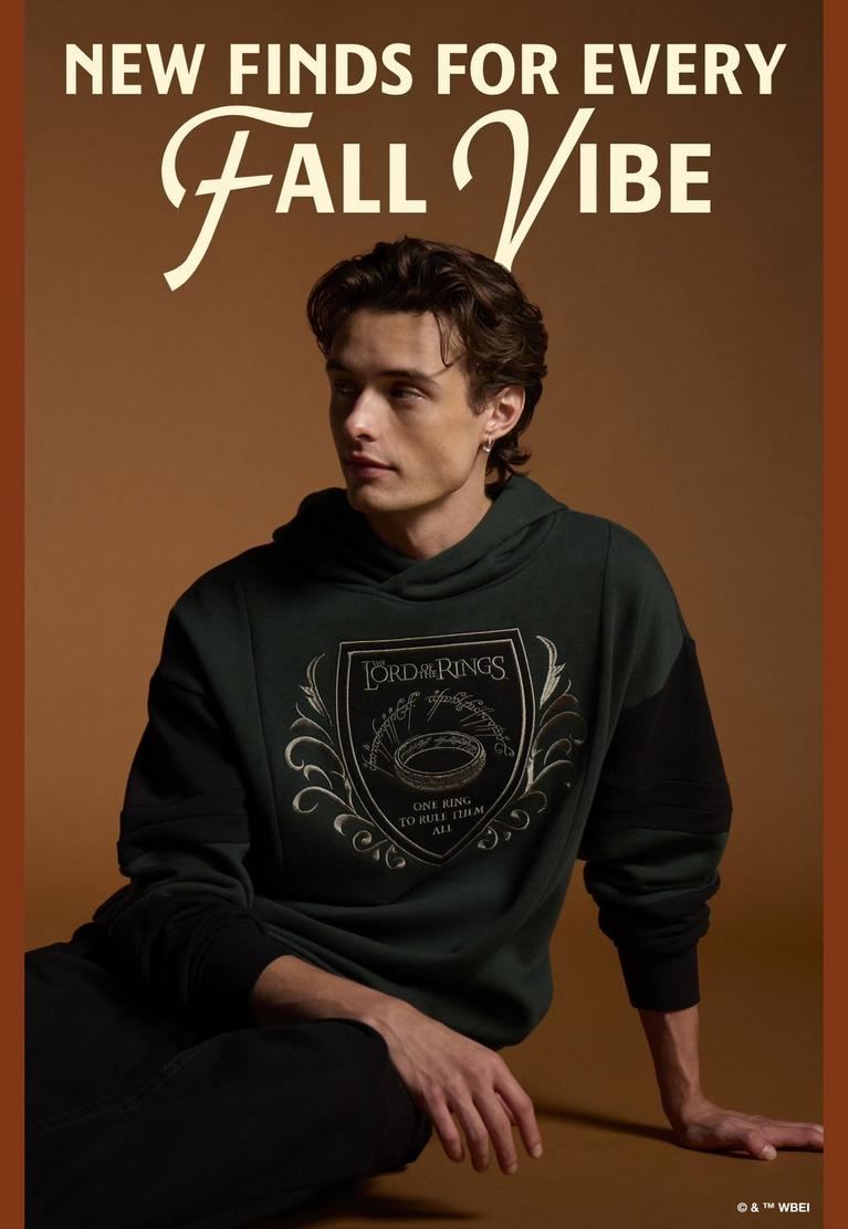 Model wearing green The Lord of the Rings graphic hoodie with “New Finds for Every Fall Vibe” text. Shop by license.