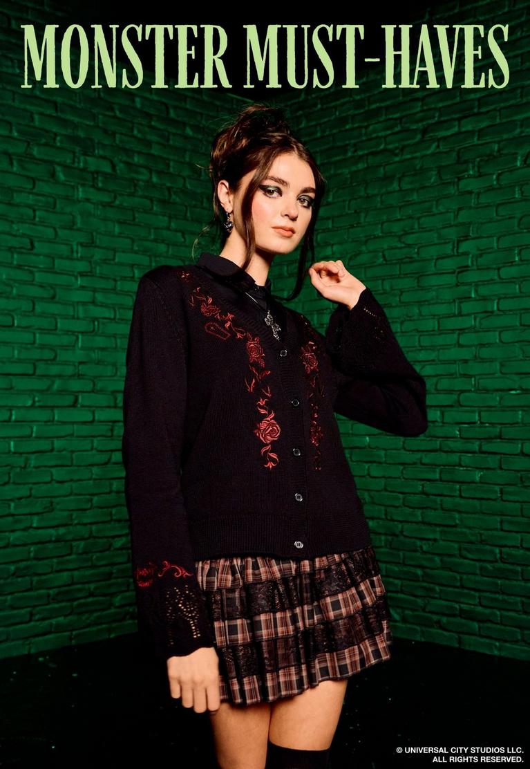 Model wearing black embroidered cardigan and plaid skirt under text “MONSTER MUST-HAVES”. Shop Universal Monsters.