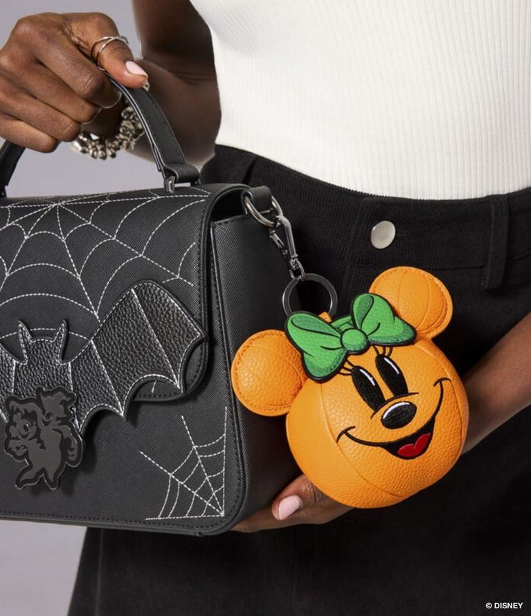 Black crossbody bag with spiderweb and bat details, plus Minnie pumpkin keychain charm. Shop bags.