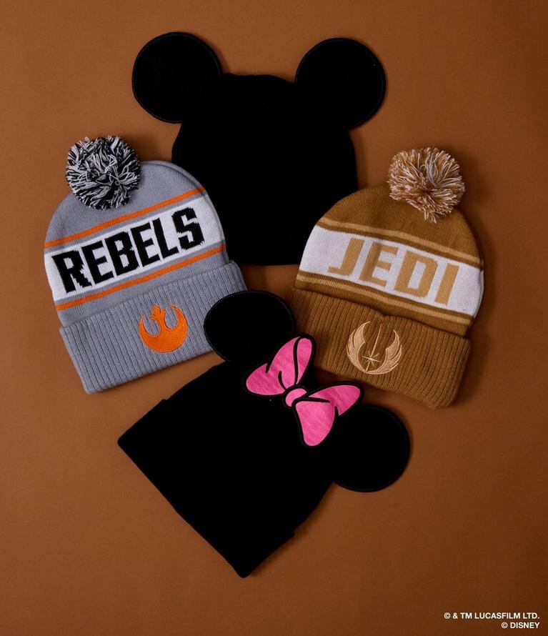 Two pom beanies reading “REBELS” and “JEDI” with Mickey and Minnie ear silhouettes. Shop cold weather accessories.