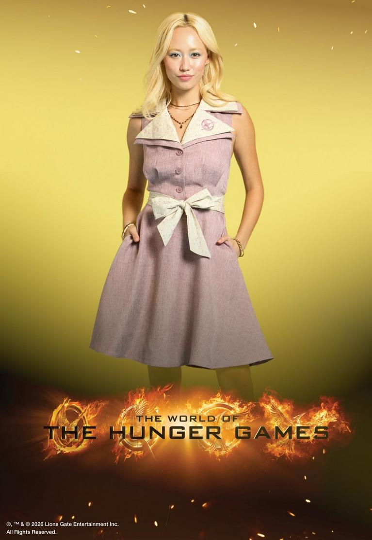 Model wearing a sleeveless belted dress with “THE WORLD OF THE HUNGER GAMES” text. Shop The Hunger Games collection.