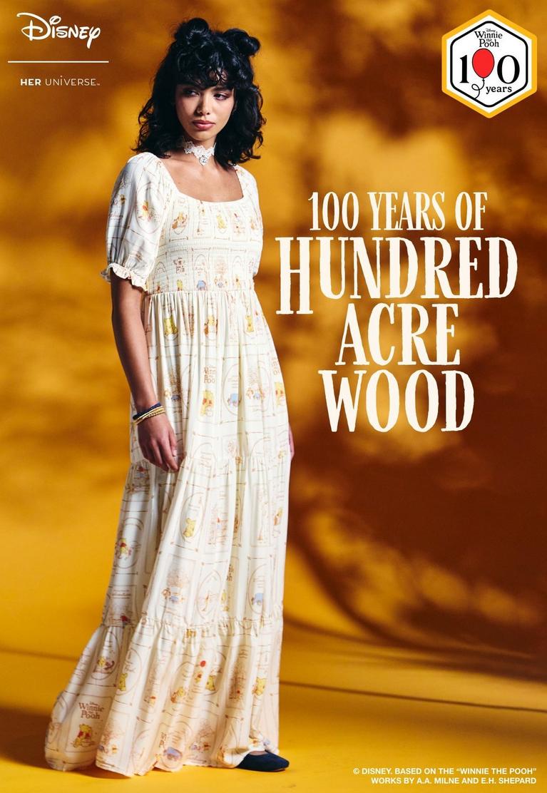 Disney Her Universe model wearing a Winnie the Pooh print maxi dress with “100 Years of Hundred Acre Wood”. Shop Winnie the Pooh.