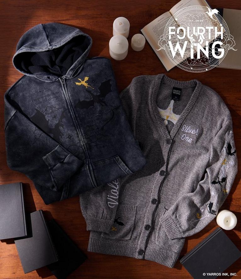 Fourth Wing hooded zip sweatshirt and “Silver One” cardigan laid flat with books and candles.