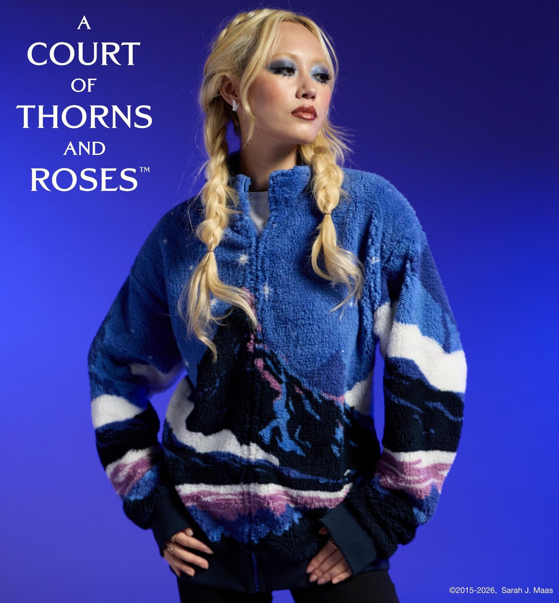 Model wearing “A Court of Thorns and Roses” fleece zip jacket with mountain print. Shop A Court of Thorns and Roses collection.