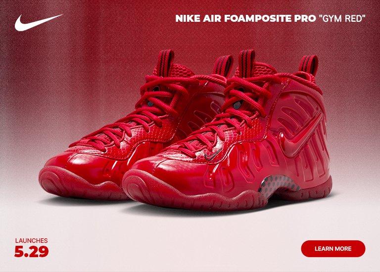 A mobile marketing banner features a pair of all-red Nike Air Foamposite Pro Gym Red sneakers against a red and white gradient background. A white Nike swoosh is in the top left corner, and the text NIKE AIR FOAMPOSITE PRO GYM RED is centered along the top. In the bottom left, text reads LAUNCHES 5.29, and a red LEARN MORE button is in the bottom right corner.