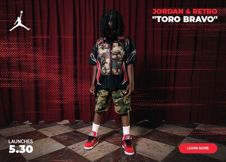 A split-screen marketing banner for the kids' Jordan 4 Retro Toro Bravo launching May 30. The left side shows a young model in a camouflage outfit and the red sneakers standing against a dark red curtain. The right side features a close-up action shot of the red, black, and grey shoes, accompanied by a Learn More button.
