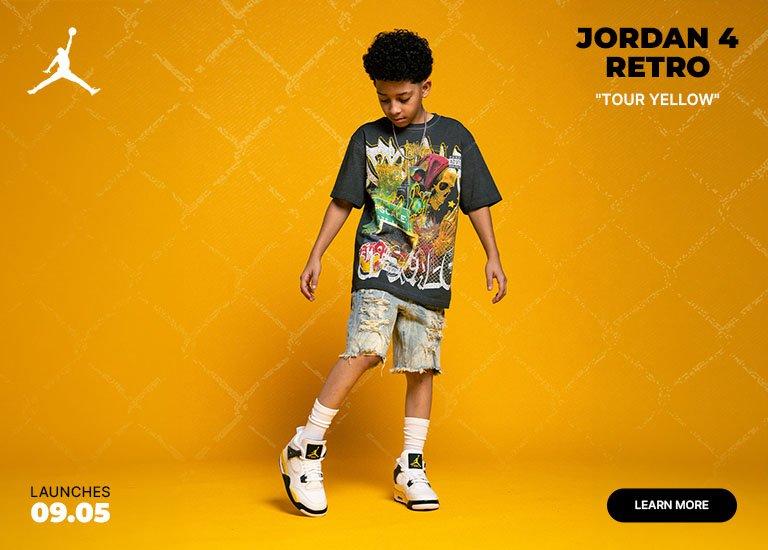 Youth model wearing the Air Jordan 4 Retro "Tour Yellow" sneakers with a graphic tee, distressed denim shorts, and white crew socks against a yellow background featuring launch date messaging.