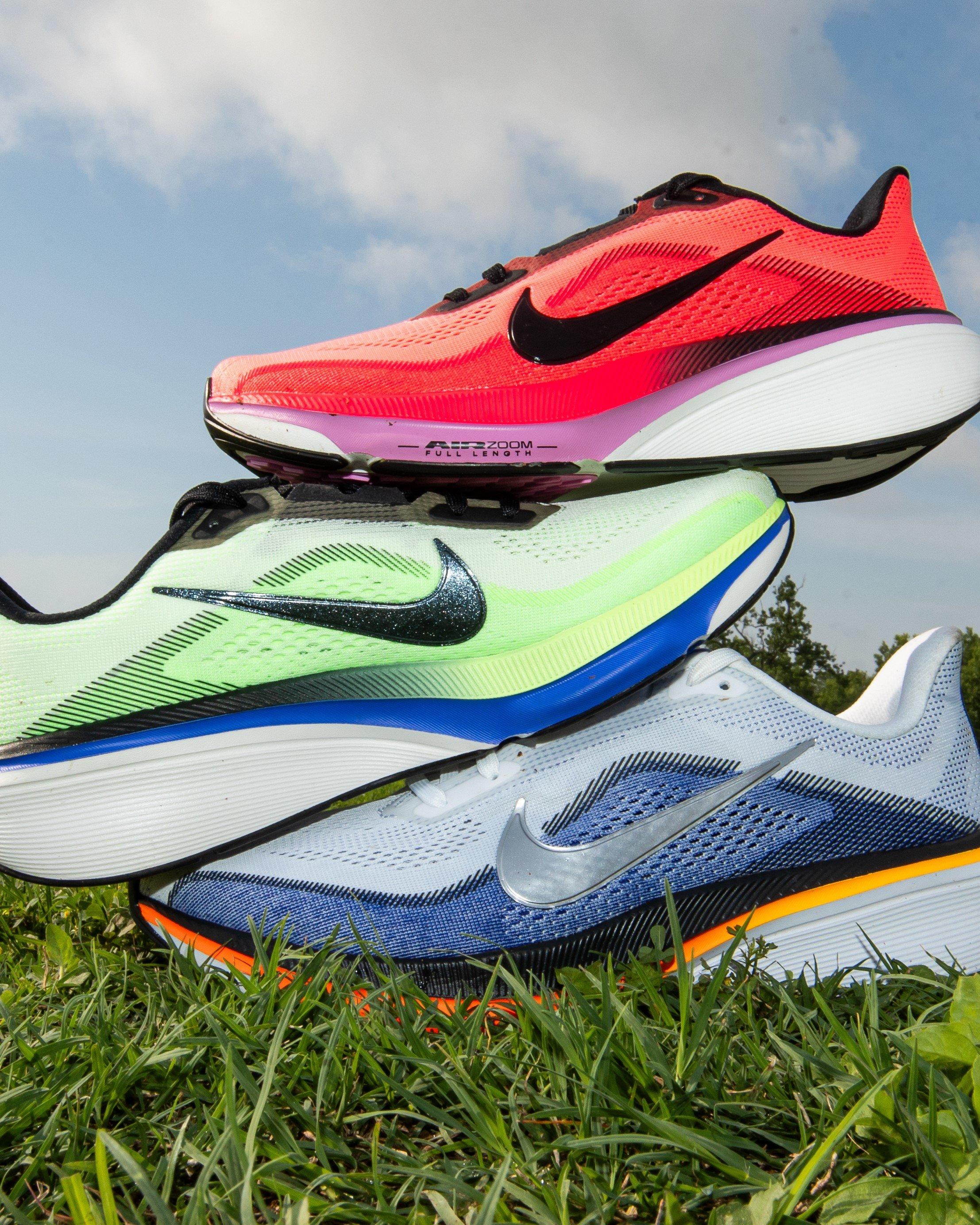 Close-up of a line of young athletes standing shoulder-to-shoulder on a track, showing legs and feet in athletic shorts and various running shoes, including bright and neutral-colored sneakers, positioned along a white starting line.