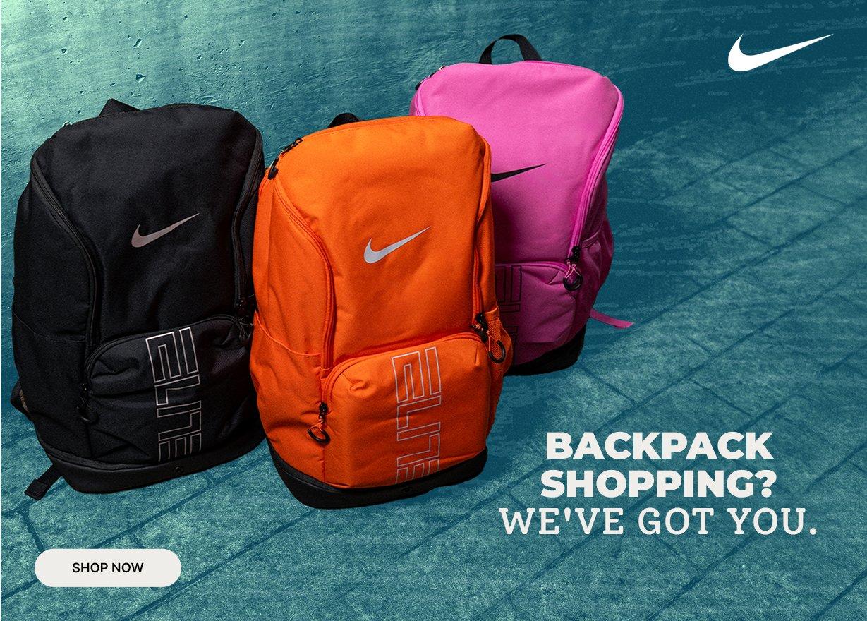 Nike backpacks in black, orange, and pink colorways displayed against a blue textured background.