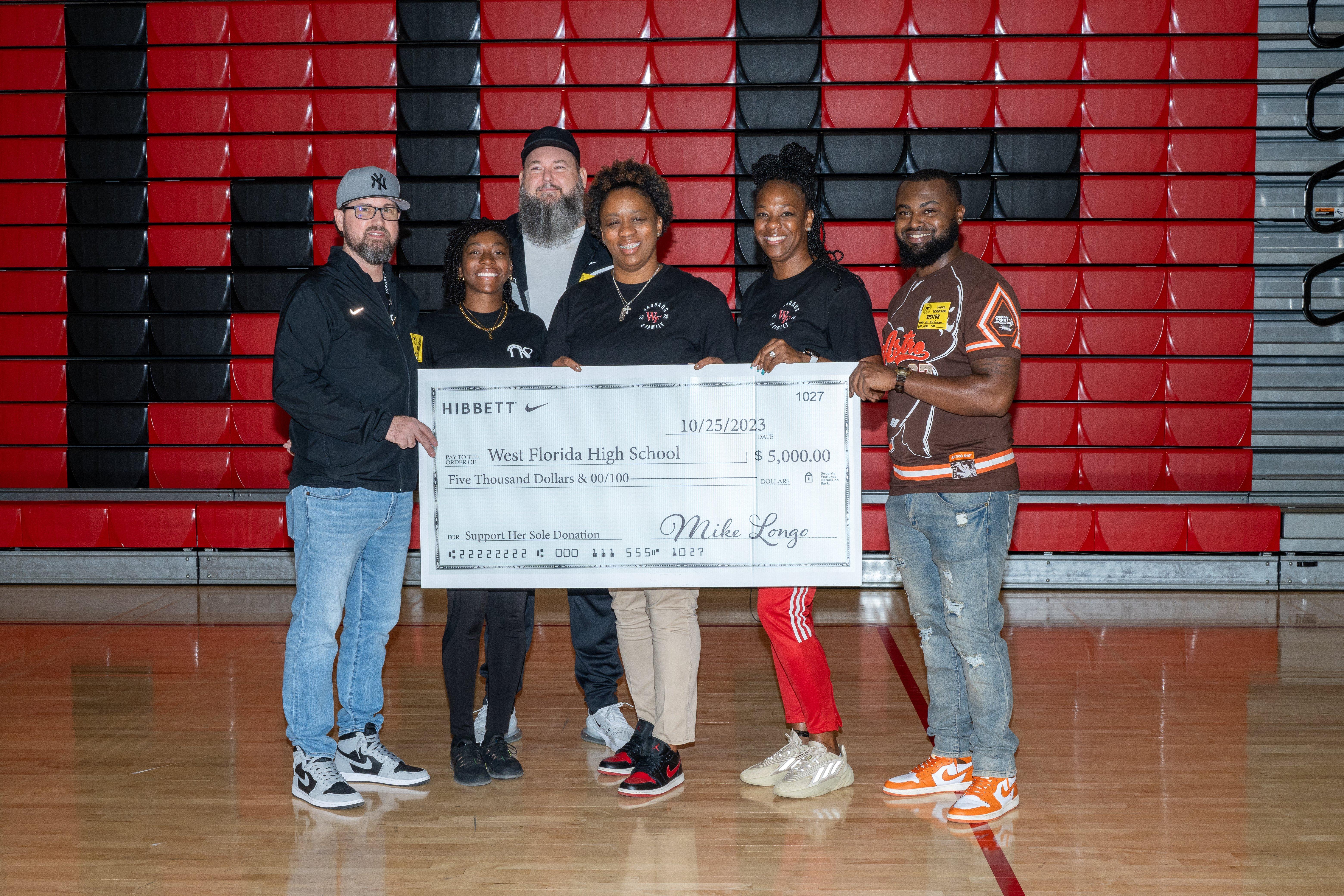 Hibbett store representatives presenting $5000 Support Her Sole donation check