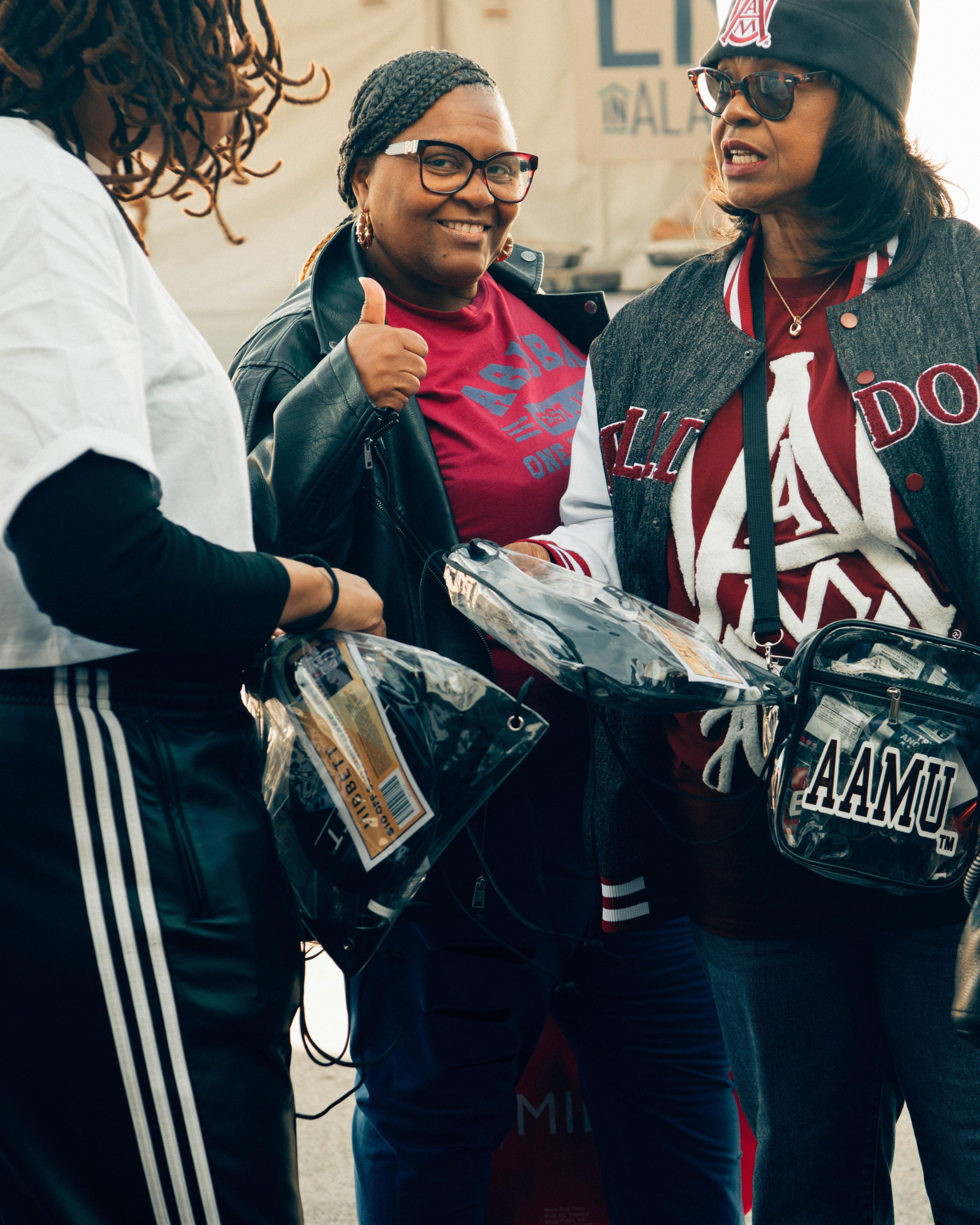 A group of people, including one holding a Hibbett branded shopping bag, smiling and posing outside the activation tent at the Magic City Classic.
