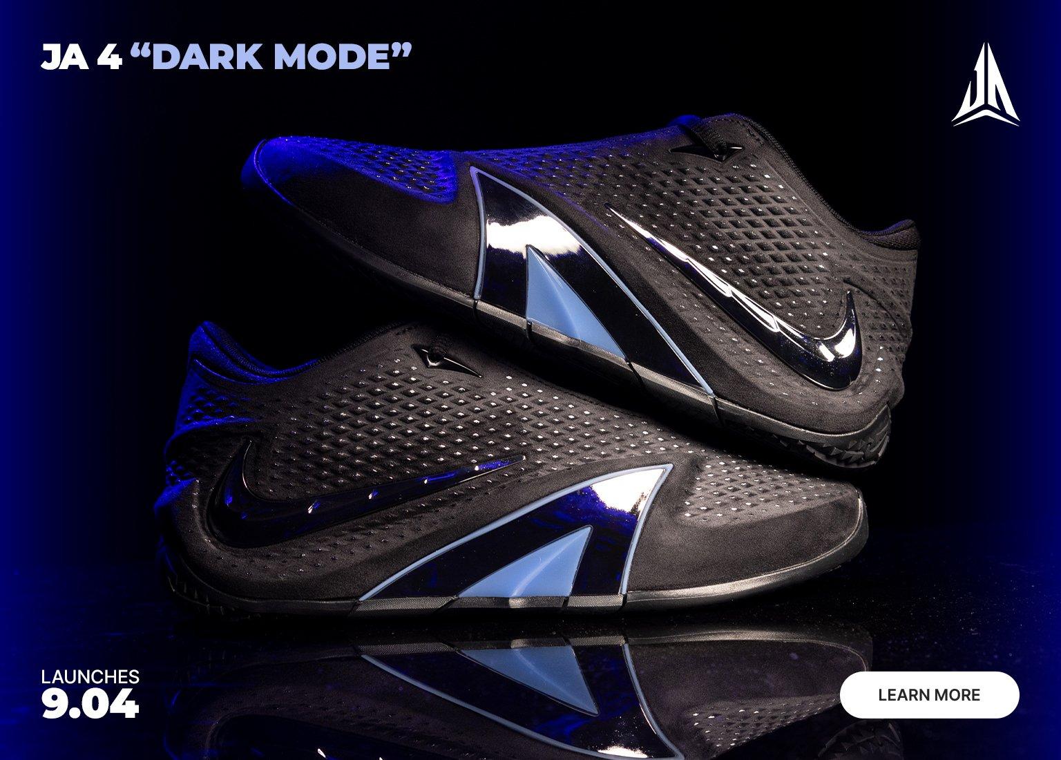 Nike JA 4 "Dark Mode" basketball shoes in black with glossy black Swooshes and reflective silver-blue midfoot panels, displayed against a dark blue background.