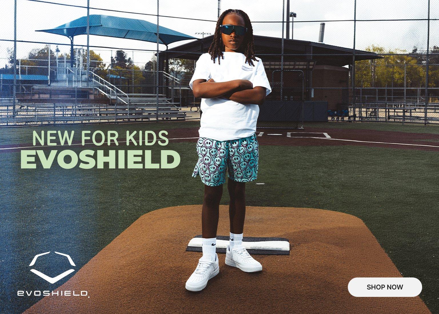 A split-screen promotional banner features a youth athlete on a baseball field wearing a white EvoShield graphic T-shirt, patterned teal shorts, and white sneakers. The left side shows the back of the shirt with "Gear Up & Pop Off" text, while the right side shows the athlete standing on a pitcher's mound. The center text reads "NEW FOR KIDS EVOSHIELD" with a "SHOP NOW" button in the corner.