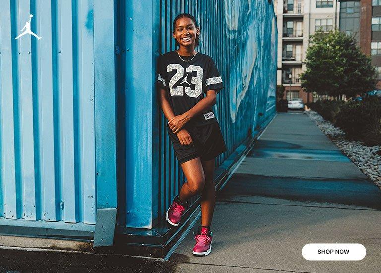 Person wearing a black Jordan jersey dress and pink Air Jordan sneakers beside a blue wall, with a close-up of the matching shoes.