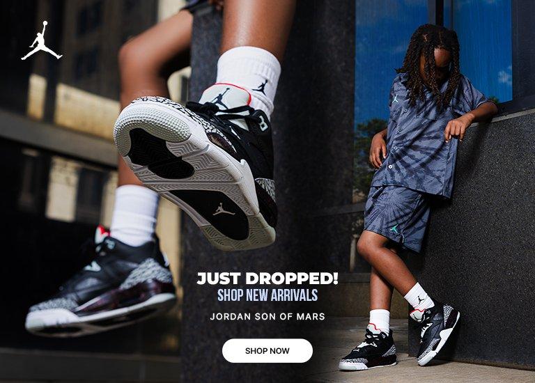 Youth model sitting on city building ledge wearing Jordan outfit and sneakers, with text Just Dropped, Shop New Arrivals, Jordan Son of Mars and Shop Now button.