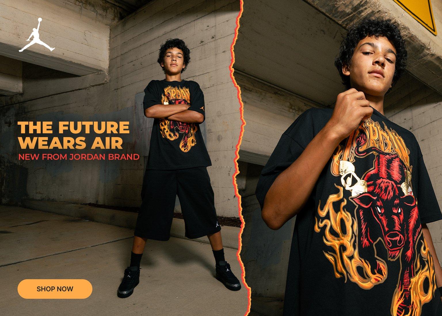 A two-panel promotional banner for Jordan Brand featuring a young male model under a concrete overpass. On the left, he stands full-length with arms crossed, wearing a black graphic t-shirt with a flaming red bull graphic, black shorts, and black Jordan sneakers next to the text "The Future Wears Air" and a "Shop Now" button. The right panel shows a close-up of the graphic t-shirt.