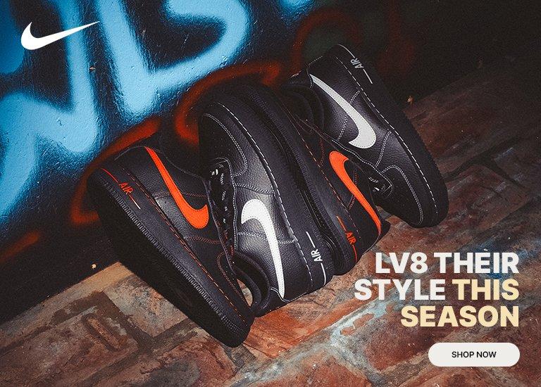Promotional image of kids’ Nike Air Force 1 LV8 sneakers in black leather with white and orange Swooshes, shown on a textured floor with the text “LV8 Their Style This Season.”