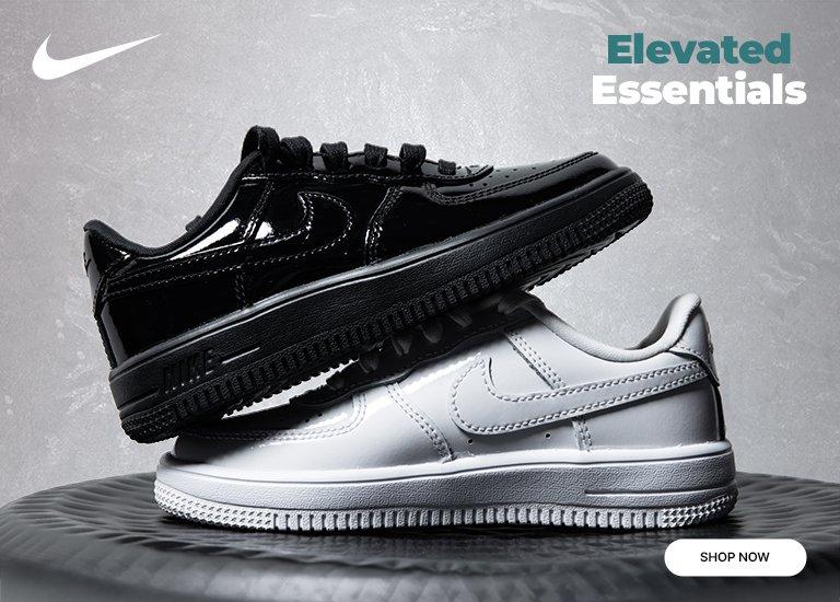 Black and white Nike sneakers stacked on a textured surface with Elevated Essentials and a Shop Now call to action.