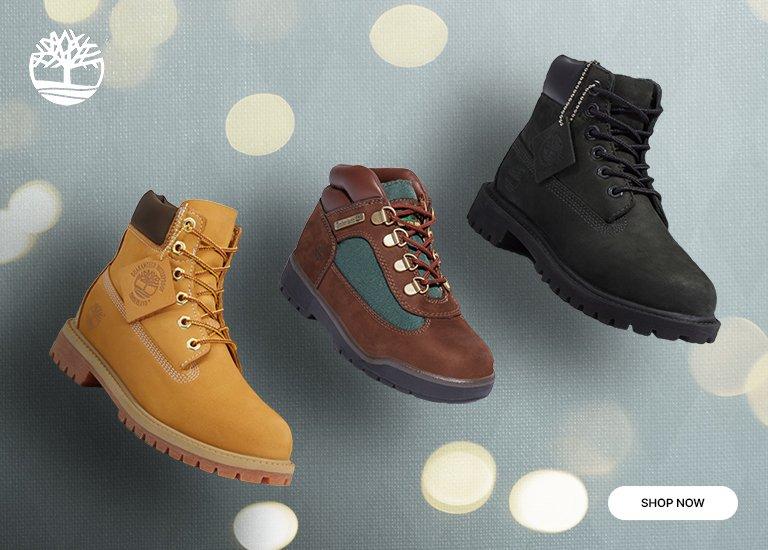 Collage showing four pairs of kids' Timberland boots in different colors (tan, brown/green, black, and beige), floating against a light grey background with lights. A Timberland logo and a SHOP NOW button are included.