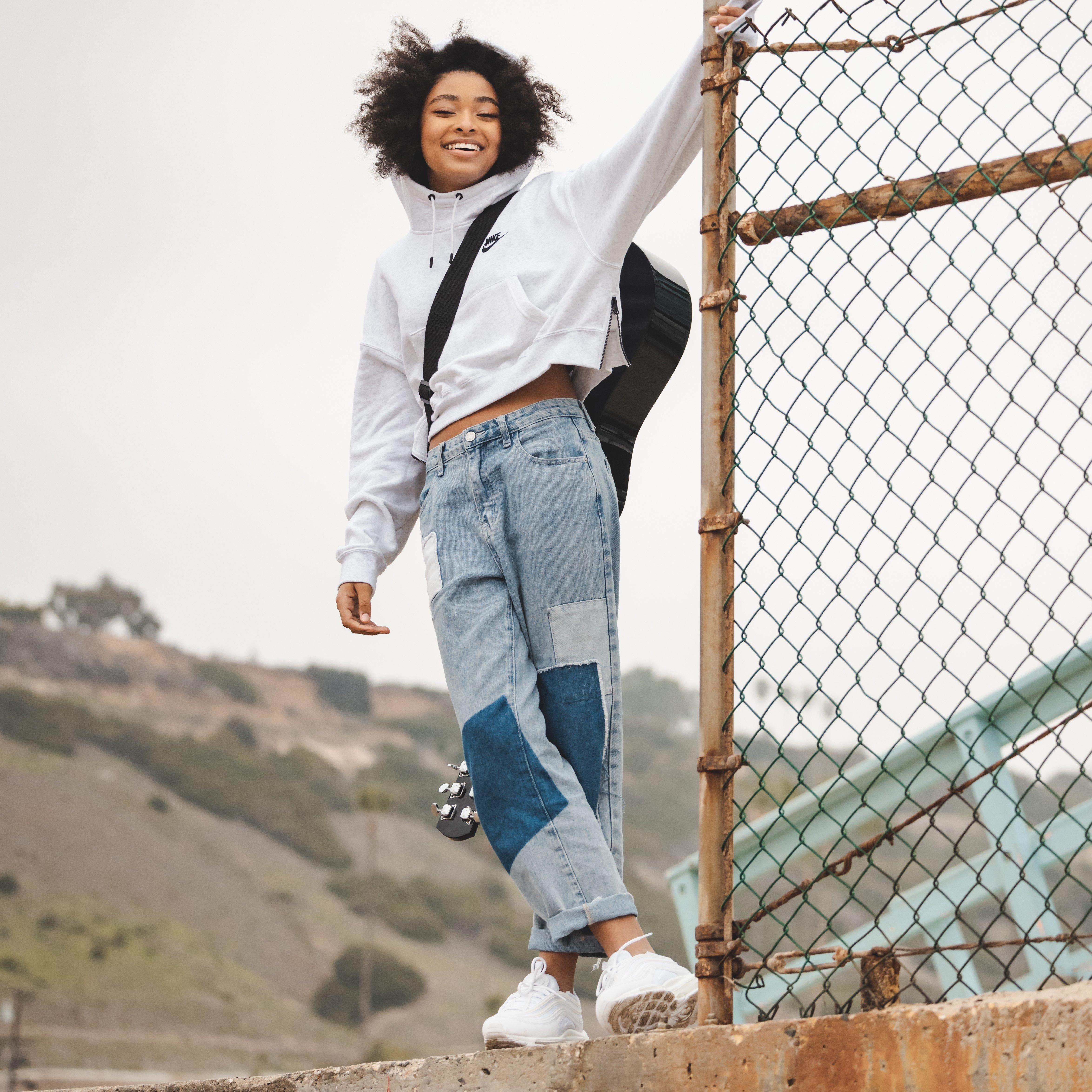 Mychal Bella posing against chain link fence during Support Her Sole filming