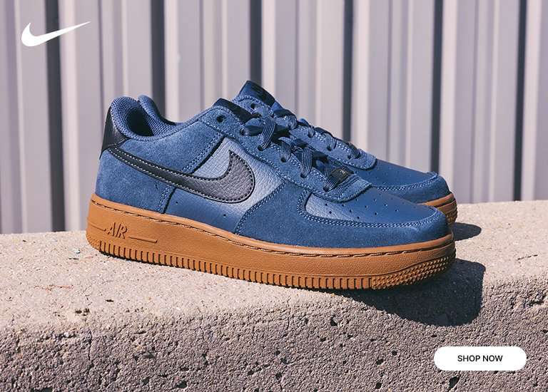 Kids' Nike Air Force One Blue Suede sneaker with Gum Bottom sitting on concrete in front of metal background.