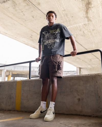 Young man modeling Smoke Rise Men's Wide Crop Pantheon Tee Black, Smoke Rise Men's Utility Cargo Nylon Short - Bison, and Nike Air Force 1 '07 LV8 "Lt Khaki/Black" Men's Shoe