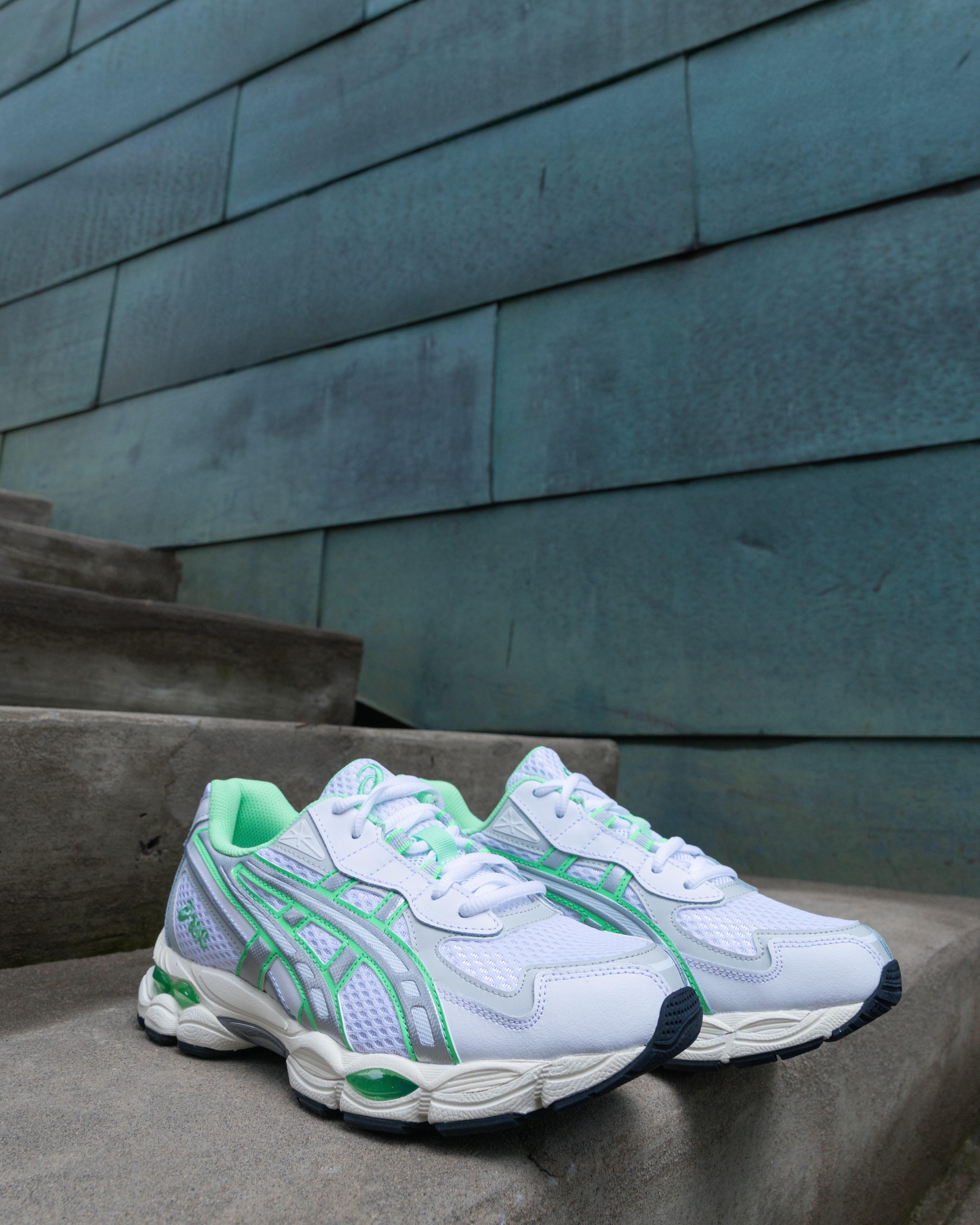  A pair of Asics GEL-2160 sneakers are shown on a concrete staircase. The shoes are white with light green and silver accents.