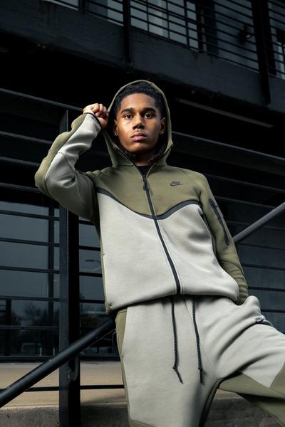 Young man in olive green Nike Tech joggers and jacket