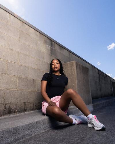 Woman sitting in Nike Women's Sportswear Chill Knit Mod, Smoke Rise Women's Woven Bungee Shorts - Pink Foam, and  Crop Tee, and Nike Zoom Vomero 5 "Photon Dust/Metallic Silver/Summit White" Women's Shoe