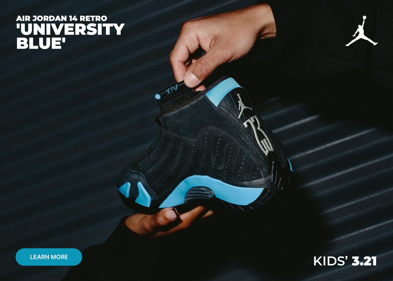 A horizontal promotional banner showcasing the Air Jordan 14 Retro University Blue in kids sizes. Two sets of hands hold the sneakers against a dark, textured background, displaying both the side profile and the heel detail. The shoes feature black suede with university blue accents on the midsole and Jumpman branding. Text on the banner includes AIR JORDAN 14 RETRO UNIVERSITY BLUE and KIDS 3.21, with a teal LEARN MORE button in the bottom left corner and a white Jumpman logo in the top right.