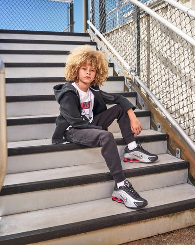 Boy modeling Nike sitting on bleachers