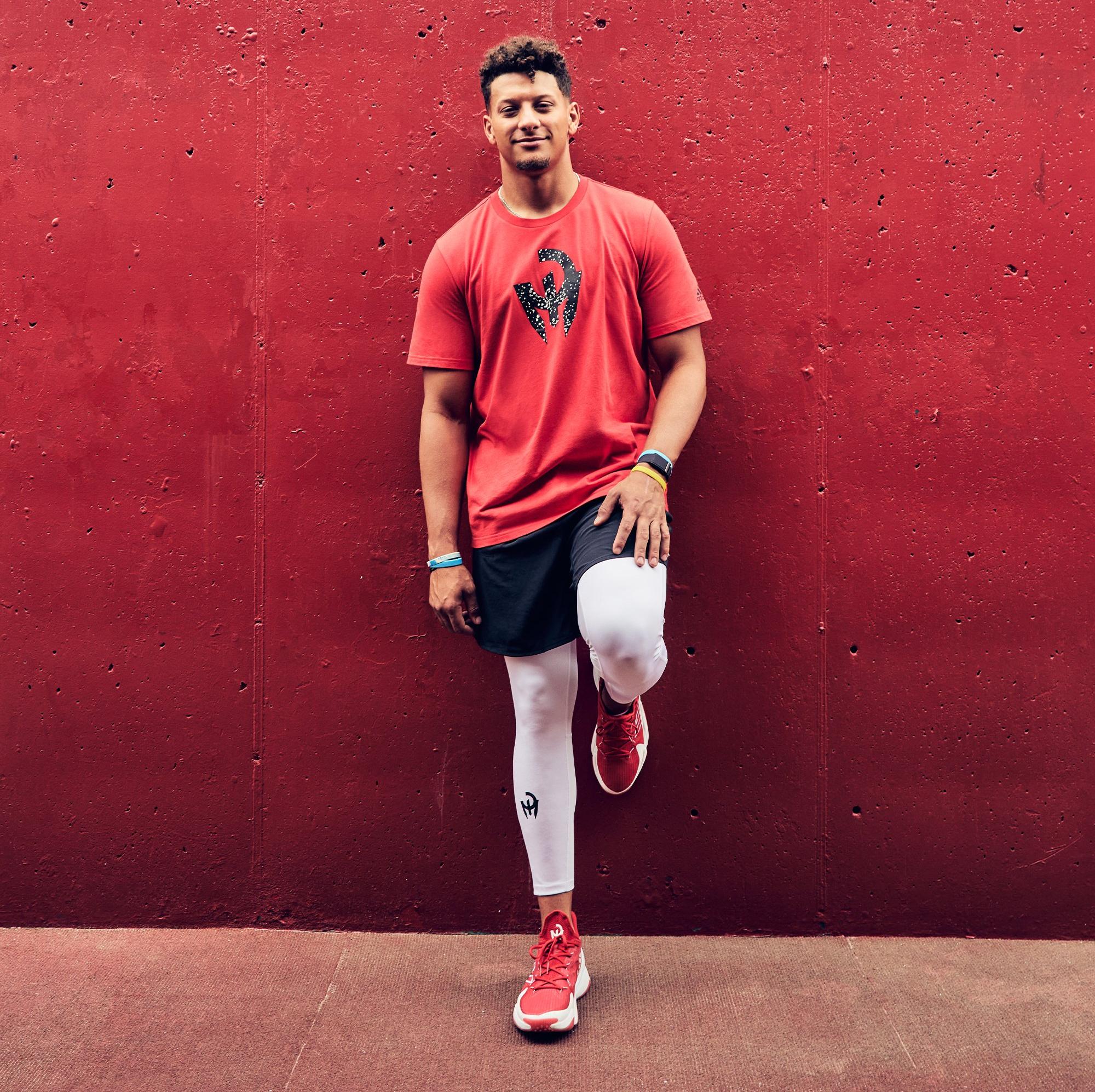 Patrick Mahomes standing on wall wearing adidas Mahomes 1 Impact FLX shoes