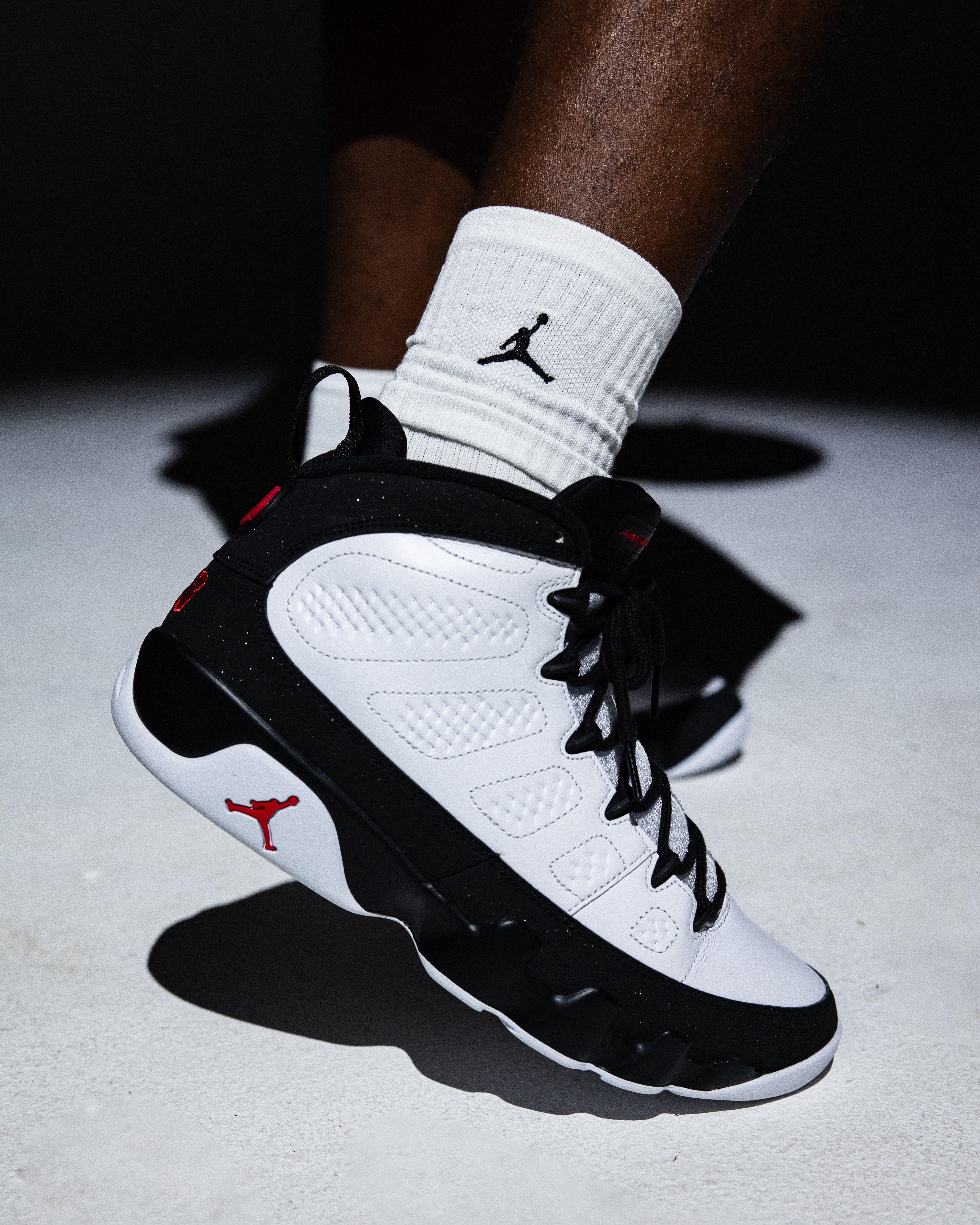 Close-up of a black-and-white Air Jordan 9 Retro Space Jam sneaker featuring black laces, red accents and a white Jordan crew sock.