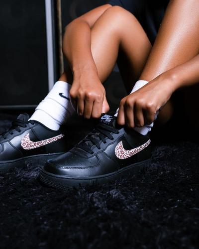 Nike Air Force 1 sneakers with leopard-print Swooshes paired with white crew socks.