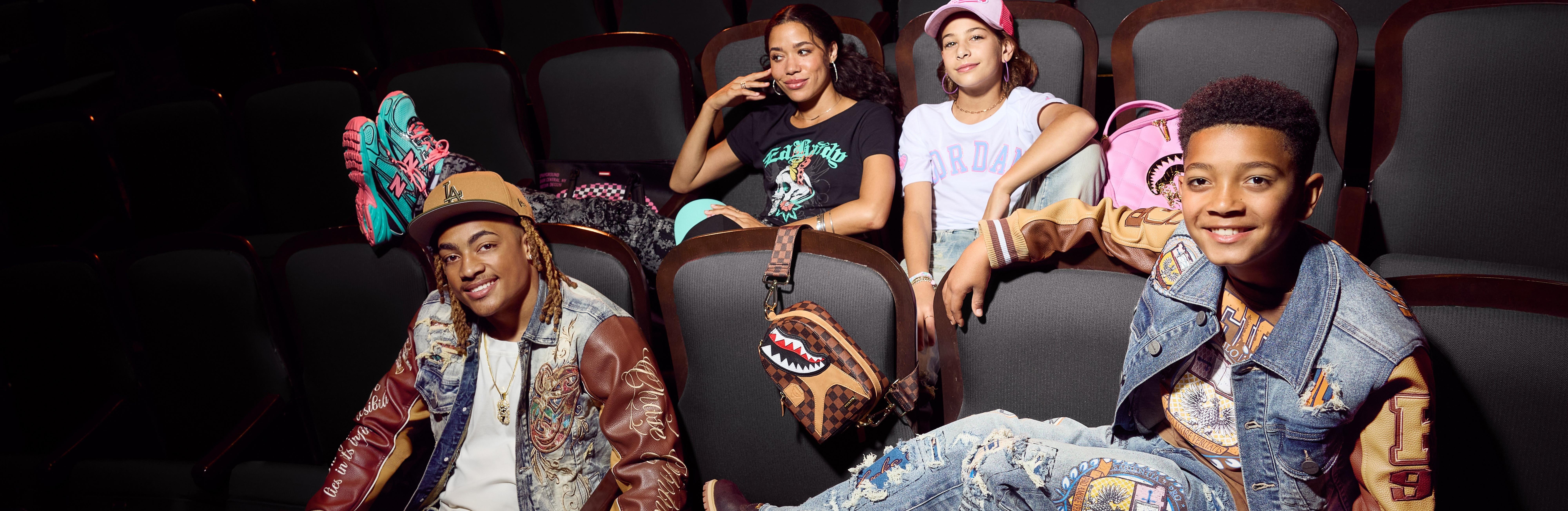 Teen girl, tween girl, teen boy and tween boy hanging out in auditorium wearing fashion apparel for back to school