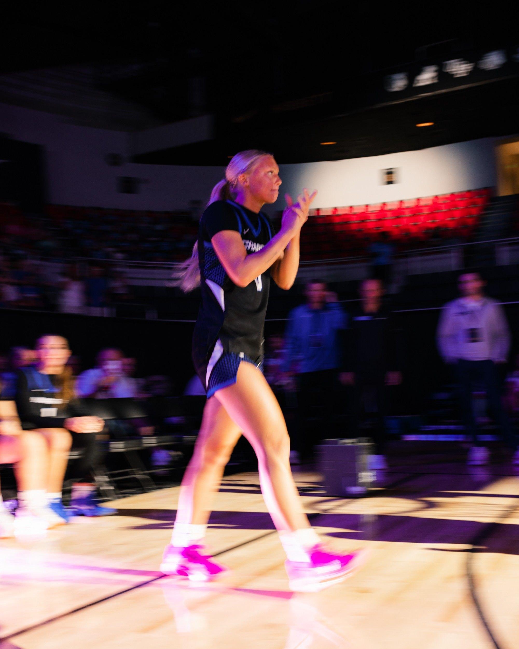 Basketball player walks onto the court under colorful arena lights during Ballin&rsquo; in Boutwell.