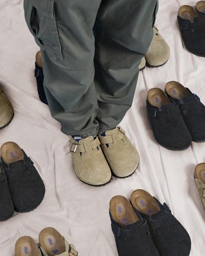 Person in taupe Birkenstock Boston shoes surrounded by more Birkenstock Boston shoes
