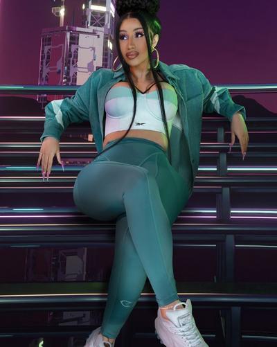 A Woman in Nike jersey, black skirt, and white on white Nike Air Force 1s