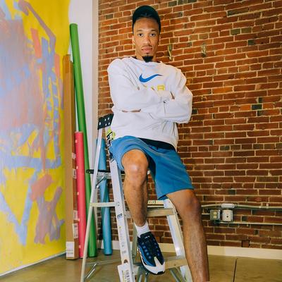 Drew Brown - The Film Lord - sitting on ladder in Nike Sweatshirt, shorts and Air Max 95s