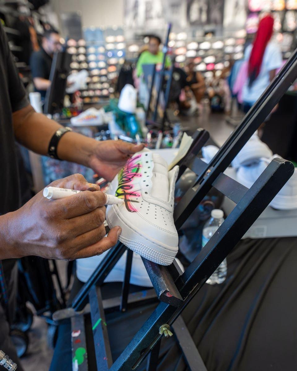 Customizing a white sneaker with colorful marker artwork at an in-store sneaker design station.