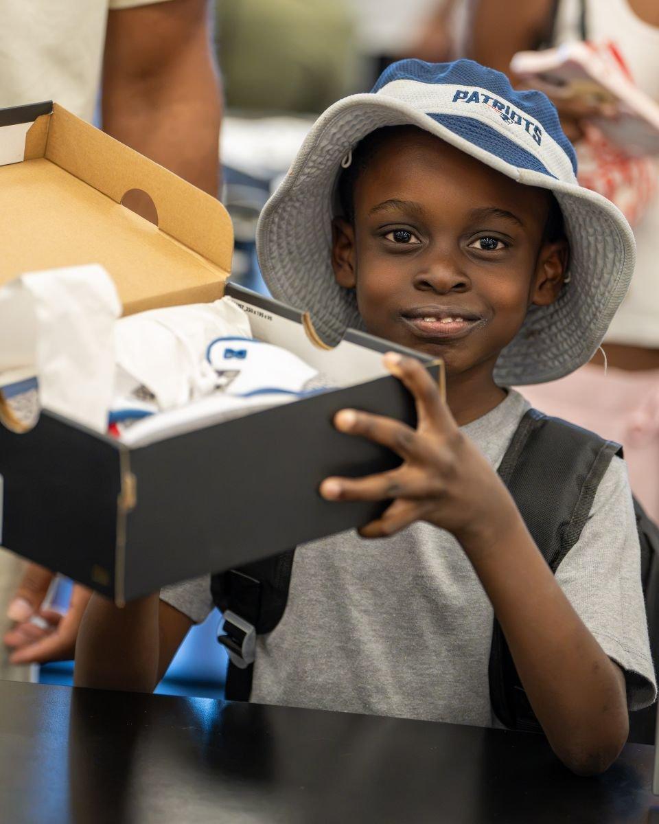Child holding a shoebox with new sneakers during a back-to-school shopping event.