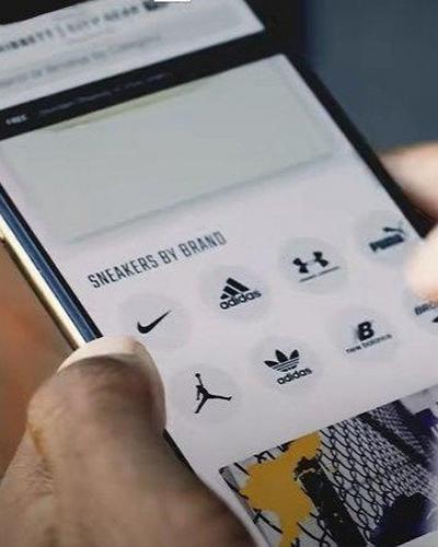 Person holding a phone with Hibbett.com displayed