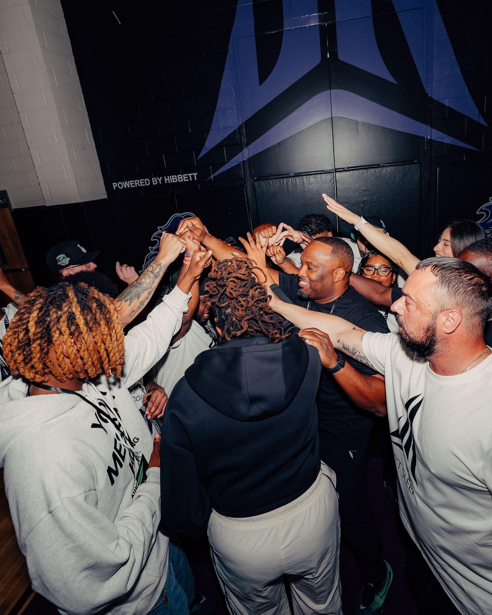 Participants gather in a team huddle beneath a Ja Morant logo mural at Crestwood High School during Hibbett and Nike's Sumter community event.