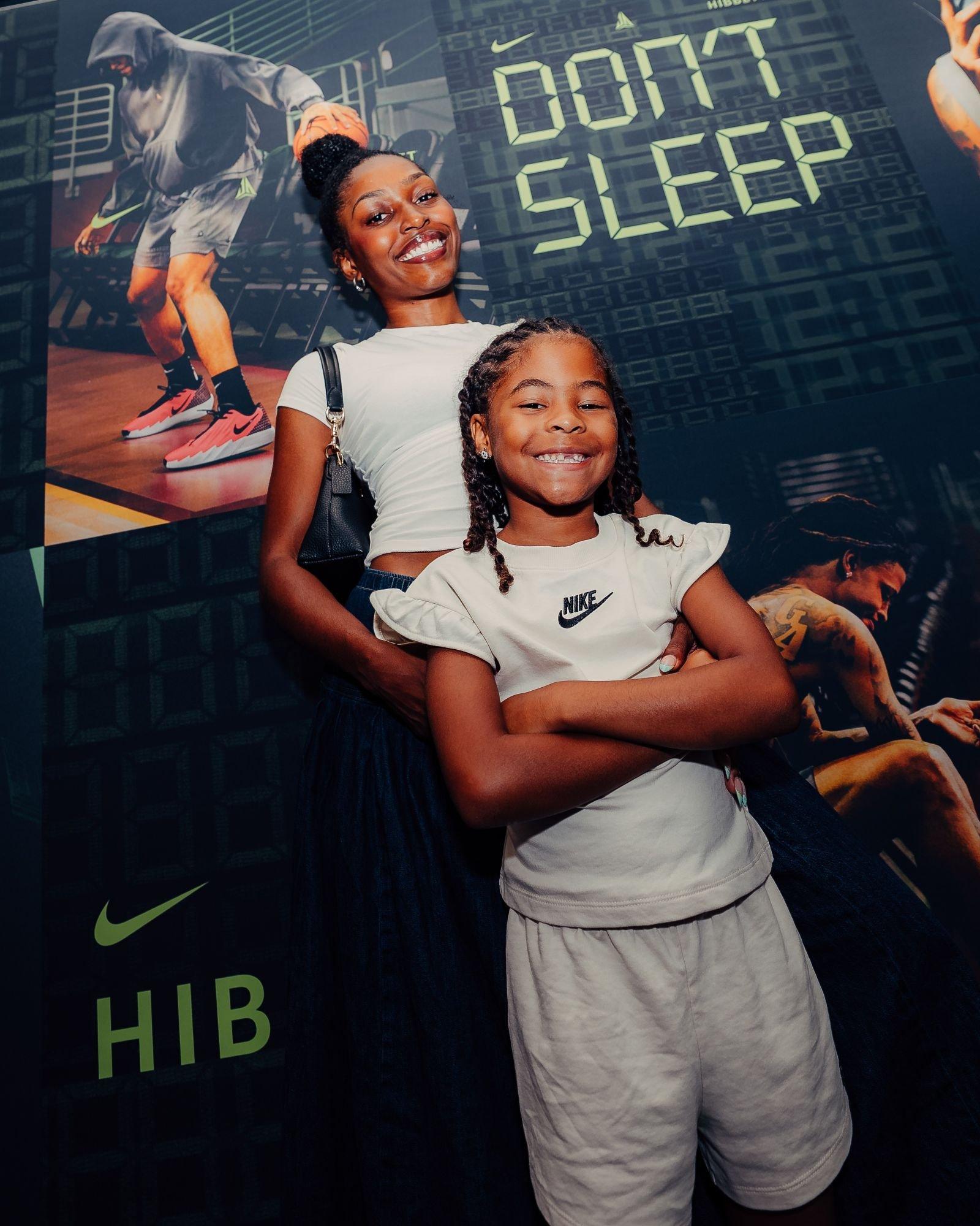 Two attendees pose in front of a "Don't Sleep" Nike and Hibbett display during the Ja Morant community event in Sumter, South Carolina.