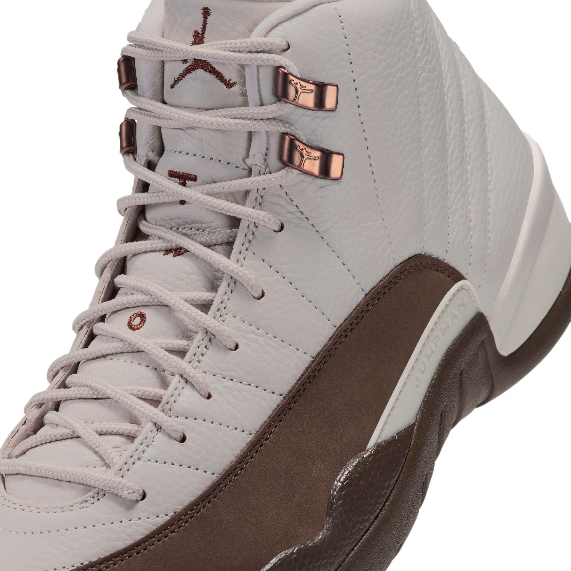 Close-up of the Jordan 12 Retro &ldquo;Fireside&rdquo; featuring cream laces, copper-toned lace hooks, a textured leather upper, and a brown mudguard.