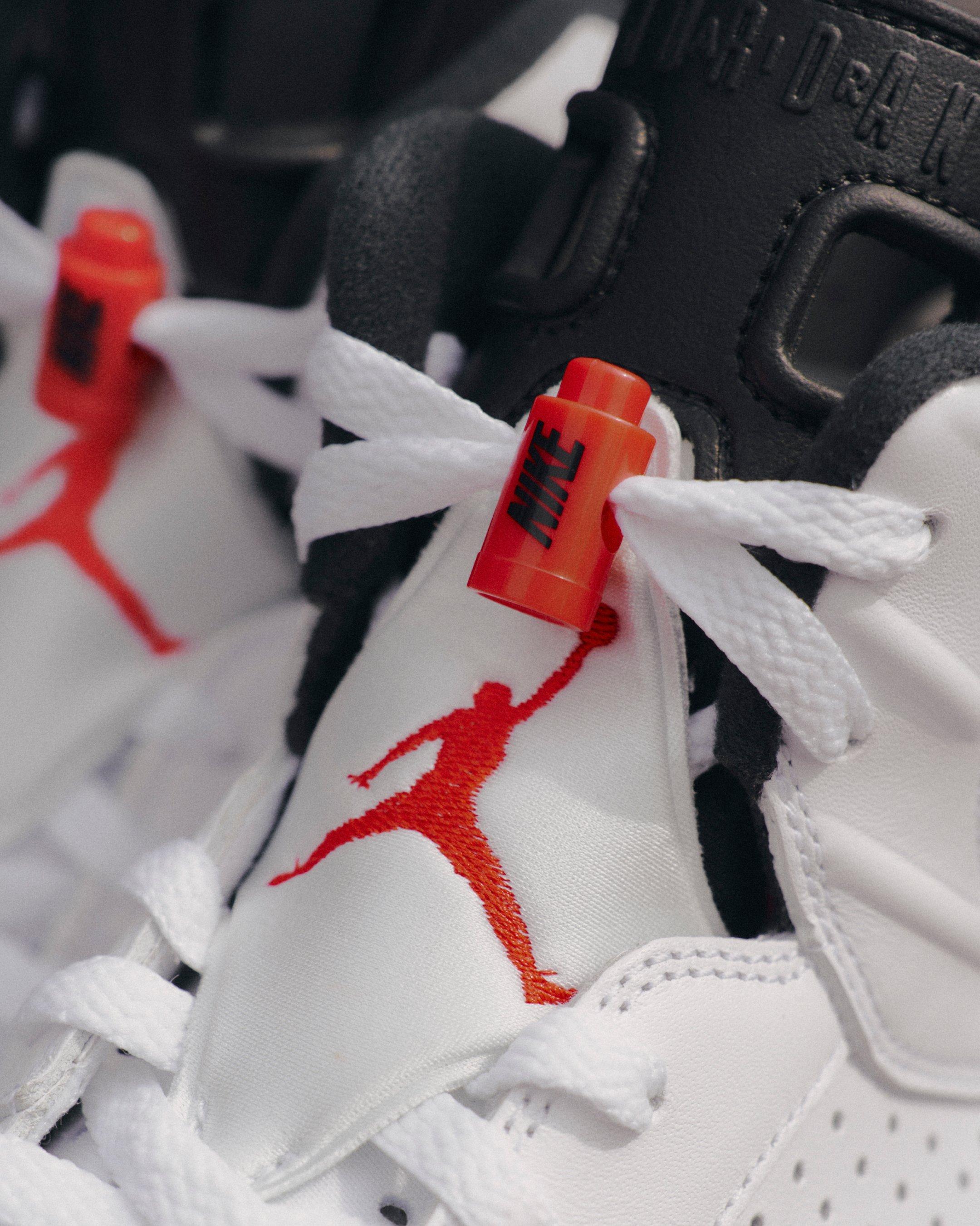 Close-up of the Jordan 6 Retro White Infrared sneaker featuring white laces, an infrared Nike lace lock, black tongue and infrared Jumpman logo.
