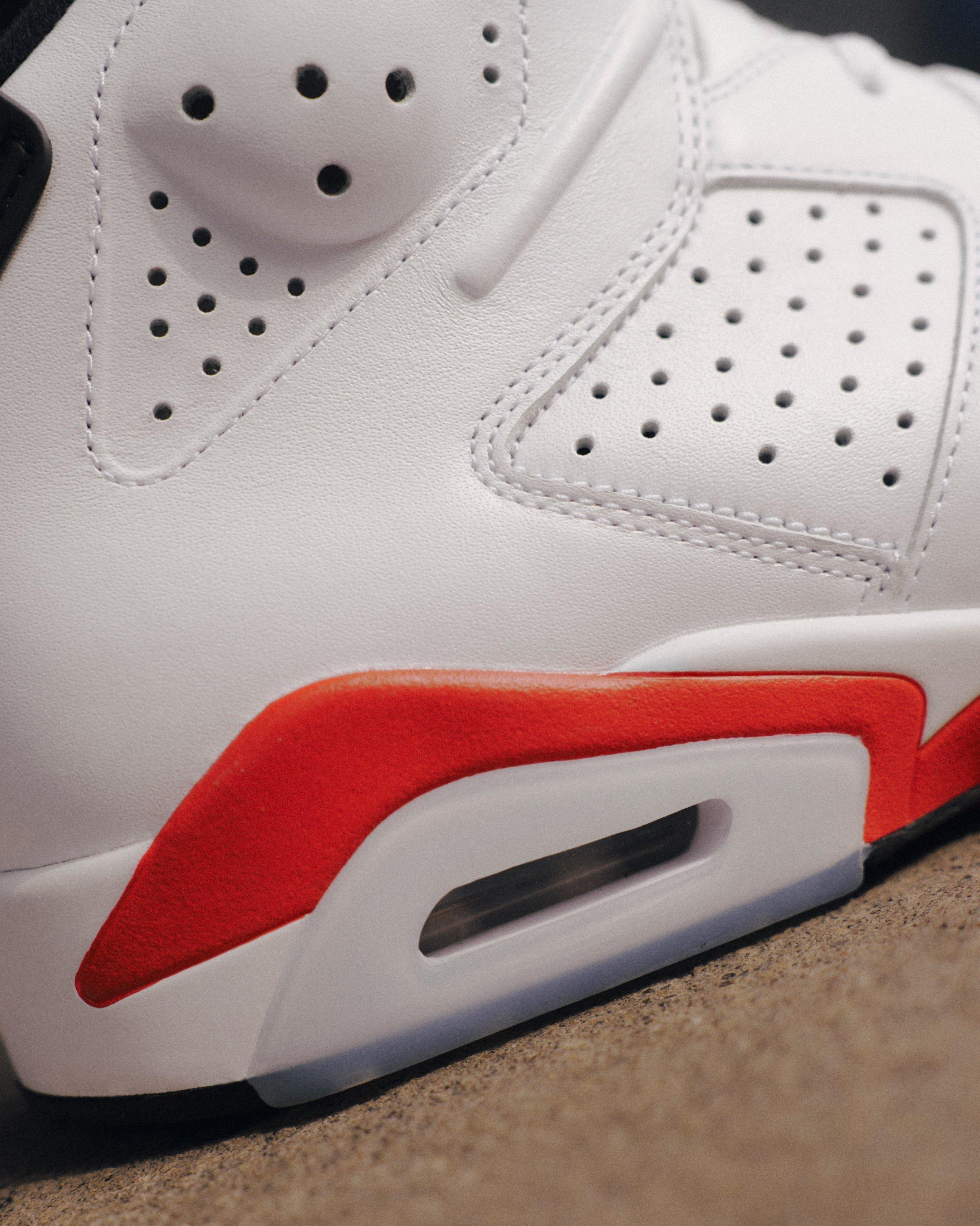 Close-up of the Jordan 6 Retro White Infrared sneaker featuring perforated white leather, an infrared midsole accent and visible Air cushioning.