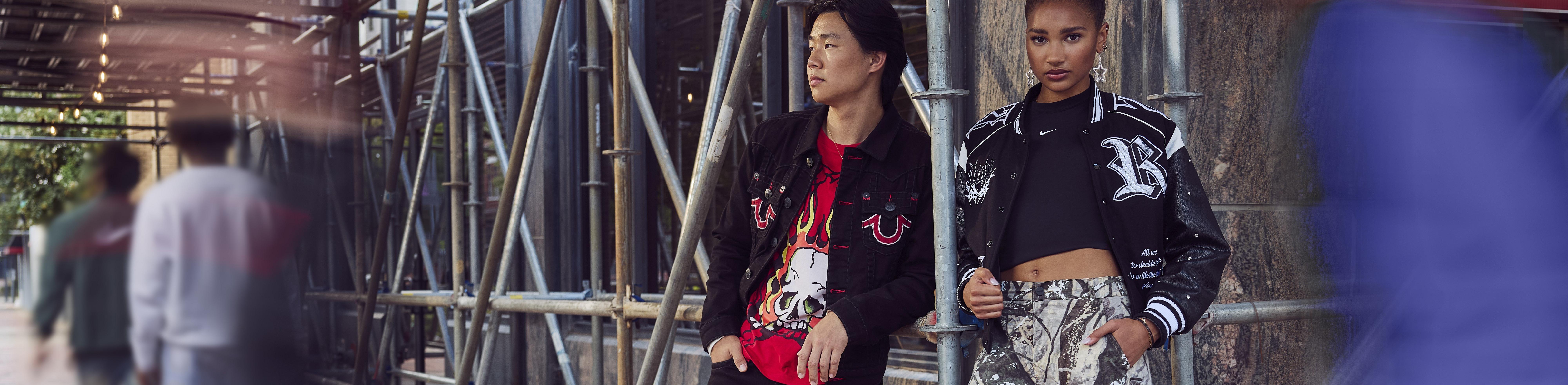 Man and Woman (teens) standing in fashion apparel under scaffolding