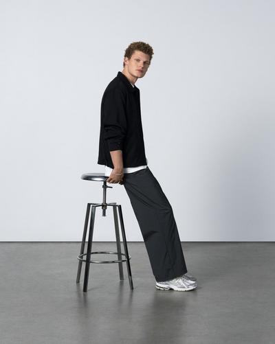 Young man in black pants and black jacket with grey New Balance 1960 