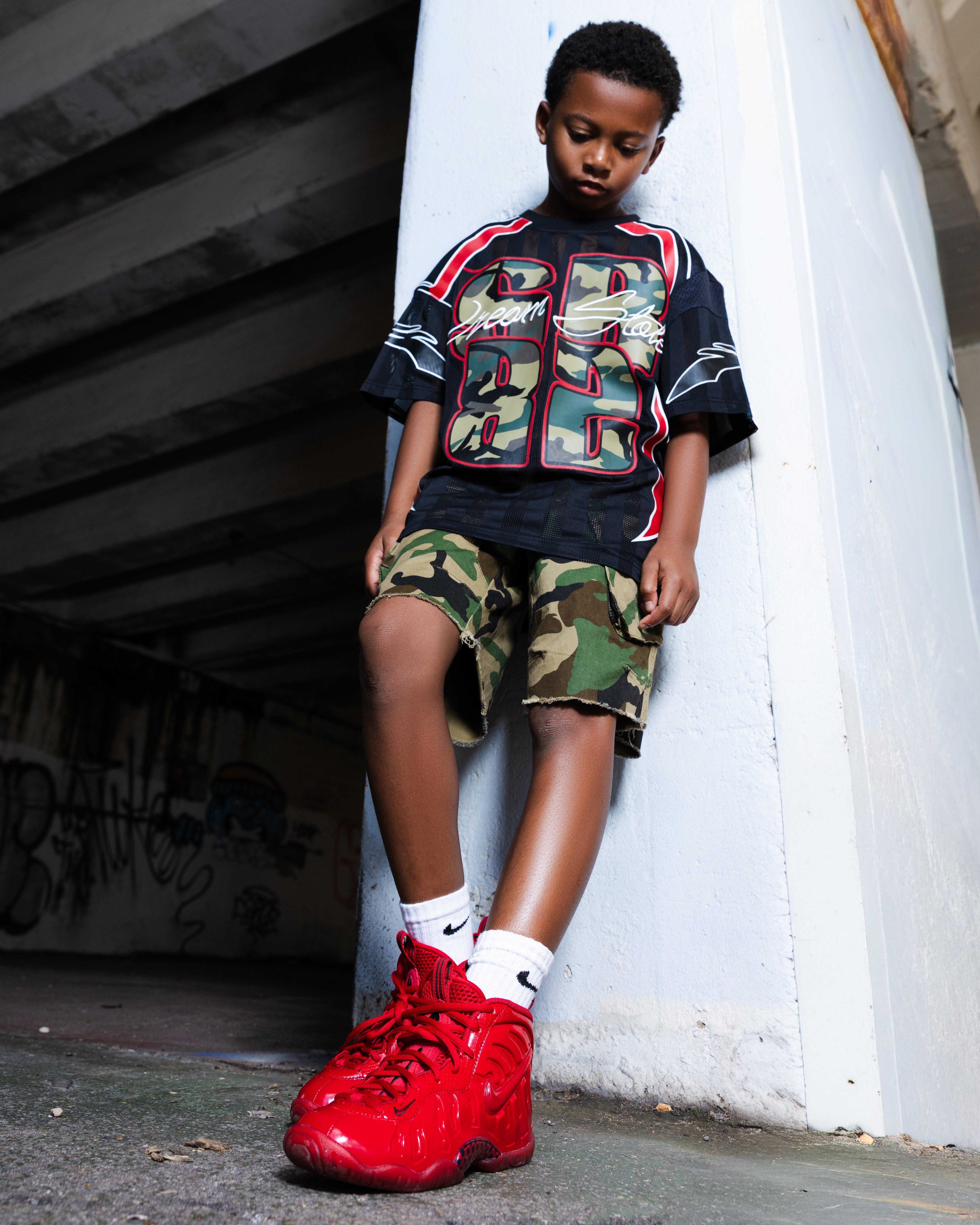 Boy in Smokerise apparel and showing Nike Air Foamposite Pro "Gym Red" side of shoe